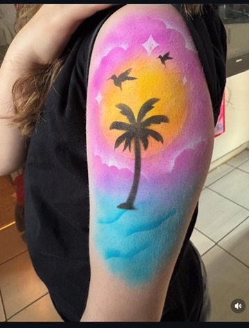 An image of an airbrush temporary tattoo featuring a tropical sunset design.